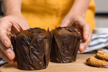 Person serving chocolate muffins on table