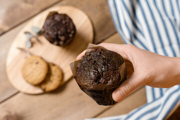 Chocolate Muffin In Hand With Cookies Nearby