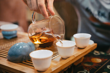 Pouring Golden Tea Into Ceramic Cups On Tray