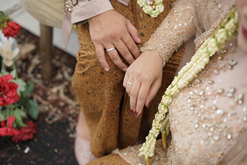 Close-up of Couple's Hands with Wedding Rings and Traditional Attire