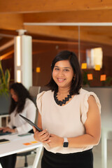 Portrait of a young working woman, of India Asian features, smiling at the office in the office