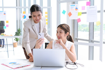 Attractive senior businesswoman train or mentor coach speaking to young woman. Two young Asian businesswomen working with laptop in the office.