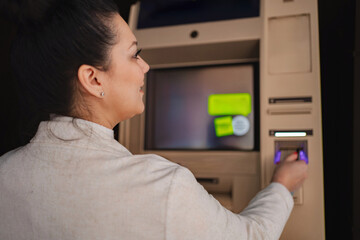 Woman using an ATM in a dimly lit urban area at night