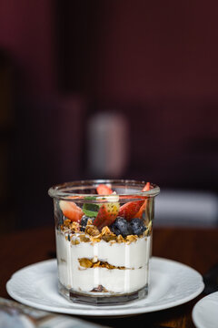 Close-up of a pot of natural yogurt with granola, fresh blueberries and strawberries