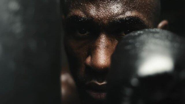 A focused boxer trains vigorously, sweat glistening on his skin, as he practices punches and footwork while preparing for a championship bout in a gym environment