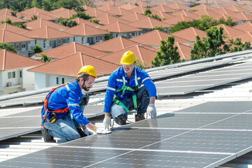 Two solar panel engineers wearing safety gear are inspecting a rooftop solar panel installation.