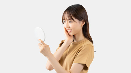 鏡で肌をチェックする若い女性
