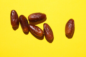 Dry tasty dates on yellow background