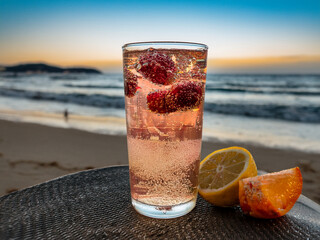 Italian soda drinks with strawberries and lemon photographed in front of beach sunsets