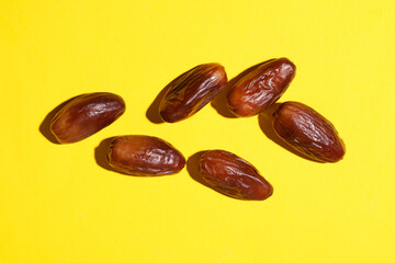 Dry tasty dates on yellow background