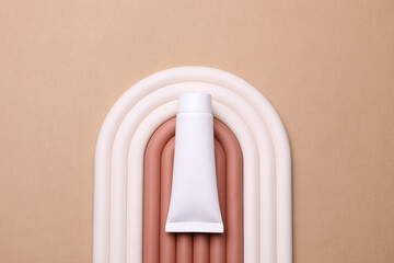 Geometric line podium with white cream tube on beige background. Creative beauty showcase. Top view. Minimalistic mockup for design