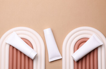 Geometric line podium with white cream tubes on beige background. Creative beauty showcase. Top view. Minimalistic mockup for design