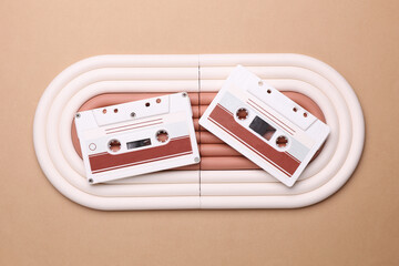 Geometric line podium with retro audio cassettes on beige background.