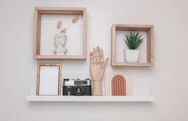 Shelf with white empty photo frame and many decorations on white background. Mockup for design....