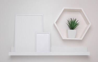 Shelf with empty photo frames and wall decor. Mockup for design