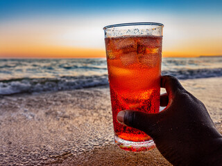 Italian soda drinks with strawberries and citrus photographed at the beach during sunset