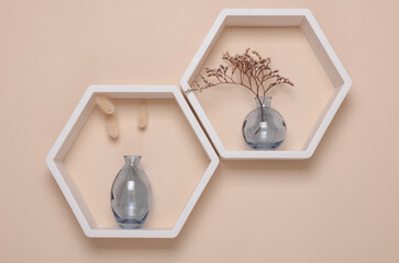 Hexagonal honeycomb shelves and vases with dry flowers on beige background. Wall decor