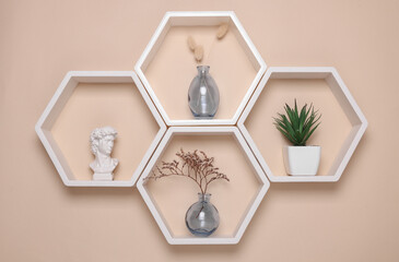 Hexagonal honeycomb shelves with decor on beige background. Wall decoration