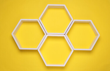 Hexagonal honeycomb wall shelves on yellow background