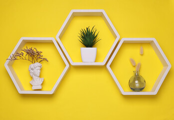 Hexagonal honeycomb wall shelves with decor on yellow background