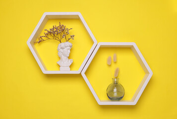 Hexagonal honeycomb wall shelves with decor on yellow background