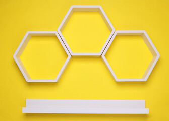 White hexagonal and straight wall shelves on yellow background