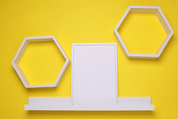 Shelf with empty photo frame and wall decor. Yellow background. Mockup for design