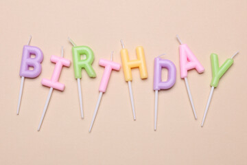 Happy birthday letter shaped candles on beige background