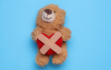 Toy bear with Medical Adhesive bandage plasters on blue background
