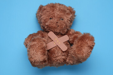 Toy bear with Medical Adhesive bandage plasters on blue background
