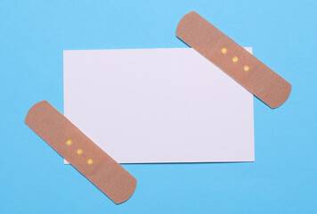 Medical Adhesive bandage plasters with white business card on blue background