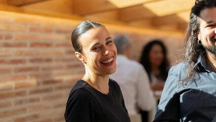 A woman smiles looking at the camera while chatting with a partner in the office