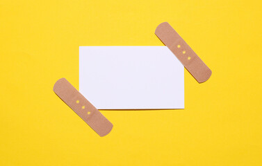 White business card with medical plaster on yellow background