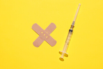 Medical Adhesive bandage plaster with syringe on yellow background