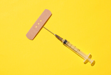 Medical Adhesive bandage plaster with syringe on yellow background