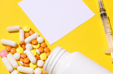 Pills with syringe and white memo card on yellow background. Copy space. Mockup for design. Medical...