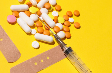 Pills with Medical Adhesive bandage plasters, syringe on yellow background. Top view