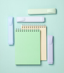 Markers or colored felt-tip pens with notebooks on pastel background. Creative layout. Top view