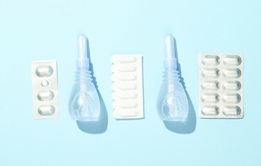 Women's health concept. Vaginal enemas, pills on blue background. Flat lay