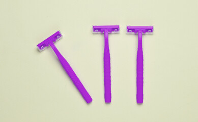 Three purple razors on a yellow background