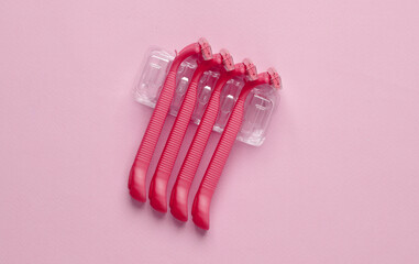 Set of plastic razors on a pink paper background