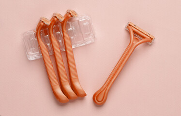 Set of plastic razors on a pink paper background