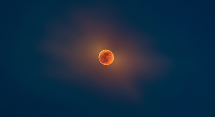 A vibrant blood moon glows intensely, surrounded by a captivating aura of deep celestial hues during a total lunar eclipse.
