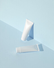 White cream tubes on blue background with shadow. Creative beauty layout. Mockup, template for...