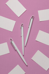 White pens with business cards on a pink background