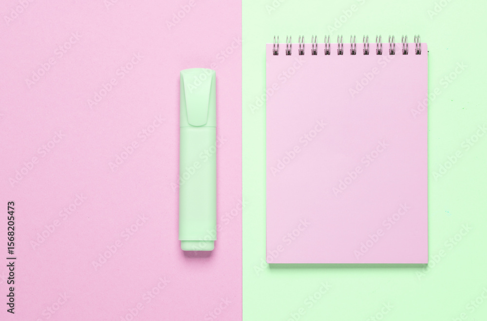 Poster notebook with a marker on a green-pink background. top view