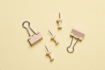 Yellow stationery accessories on a yellow background. Paper clips and pins. Monochrome photography. Flat lay. Top view
