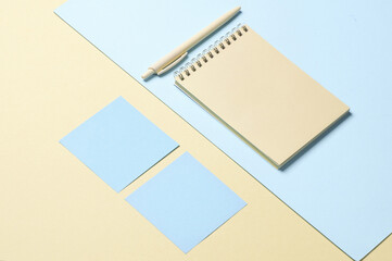 Notebook with memo papers, pen on a blue-yellow pastel background. Creative layout