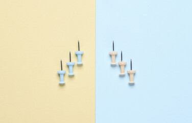 Stationery pins on a yellow blue pastel background.