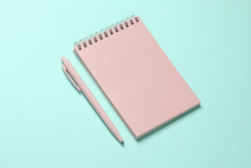 Pink notebook with a pen on blue background. Minimalism